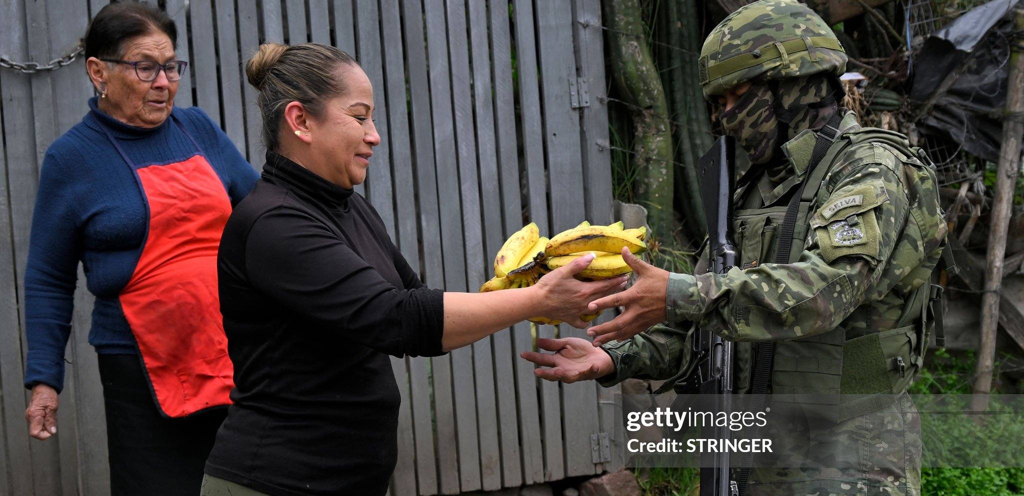 Жінка дає банани військовослужбовцю під час патрулювання в районі Луча-де-лос-Побрес на півдні Кіто. Еквадор / Фото Getty Images