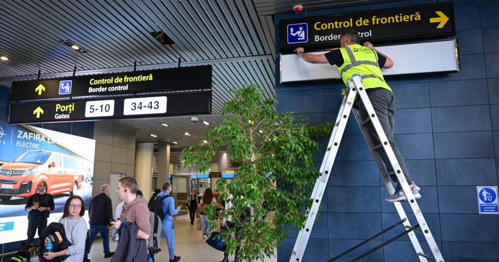 Румынский рабочий меняет указатели для пассажиров в Международном аэропорту имени Анри Коанды перед тем, как Румыния и Болгария сделают первый шаг в Шенгенскую зону безвизового передвижения / Фото AFP