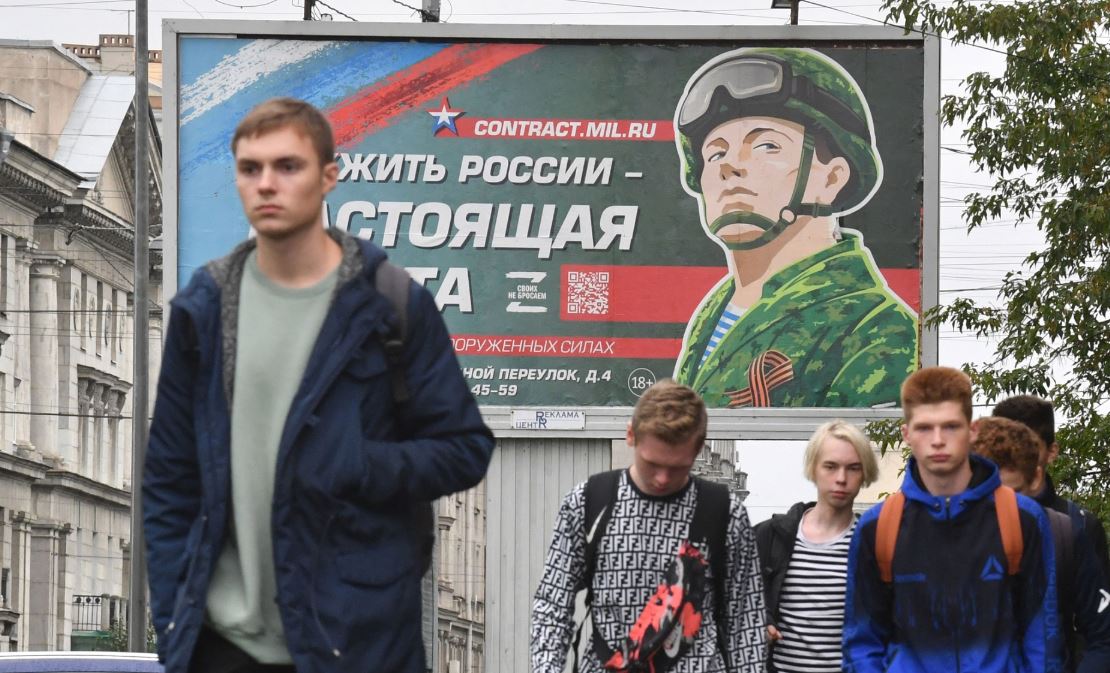 Молоді люди проходять повз табло, що рекламує службу в армії за контрактом. Санкт-Петербург, Росія / Фото: Getty Images