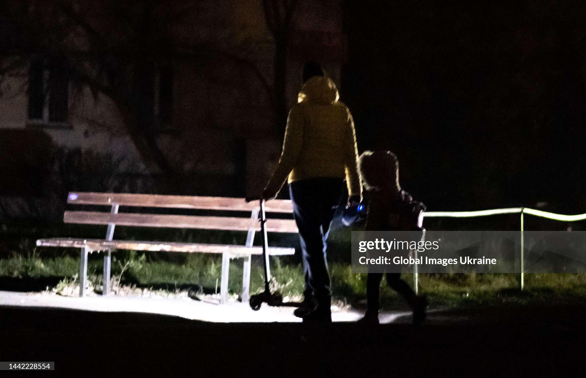 Женщина с ребенком идут по улице, освещая дорогу фонариком во время отключения электроэнергии 15 ноября 2022 года в Киеве / Фото Getty Images