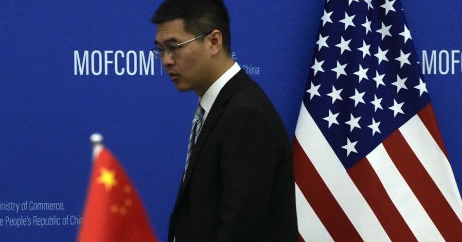 Китайский чиновник проходит мимо государственных флагов Китая и США перед встречей министра торговли США Джины Раймондо и министра торговли Китая Ван Вэньтао в Министерстве торговли в Пекине, 28 августа 2023 года / Фото AFP