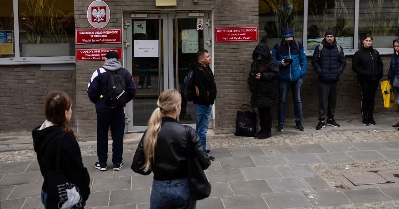 Люди стоят в очереди в отделении департамента иностранных дел в Варшаве, чтобы подать заявление на получение вида на жительство / Фото FT