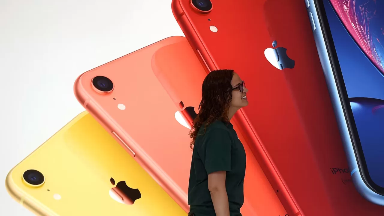 Сотрудница Apple Store проходит мимо иллюстрации iPhone в новой Библиотеке Карнеги во время торжественного открытия и медиа-презентации в Вашингтоне, 9 мая 2019 года / Фото Reuters