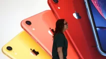 Сотрудница Apple Store проходит мимо иллюстрации iPhone в новой Библиотеке Карнеги во время торжественного открытия и медиа-презентации в Вашингтоне, 9 мая 2019 года / Фото Reuters