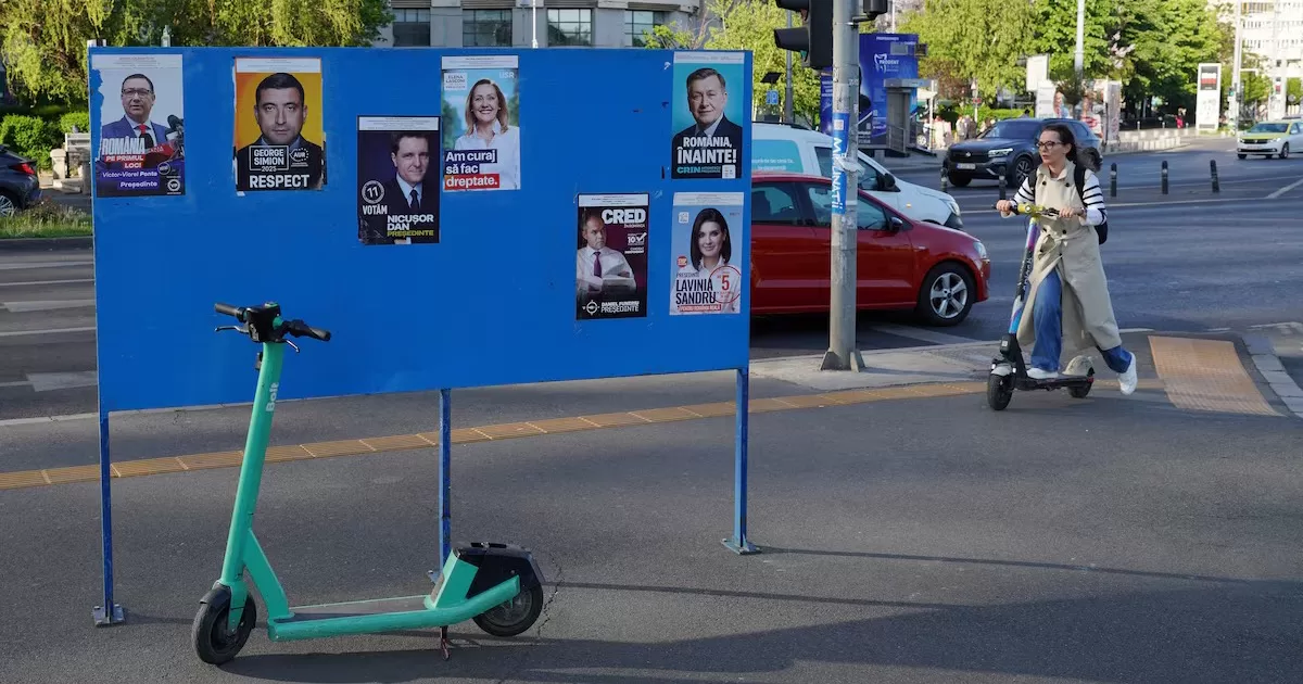 Женщина едет на самокате мимо предвыборных плакатов перед президентскими выборами в Румынии, Бухарест, 29 апреля 2025 / Фото Reuters