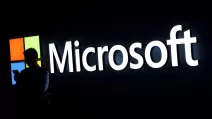 Чоловік дивиться у свій телефон на фоні логотипу Microsoft під час Всесвітнього мобільного конгресу (MWC) 2025 року в Барселоні, 3 березня 2025 / Фото Reuters