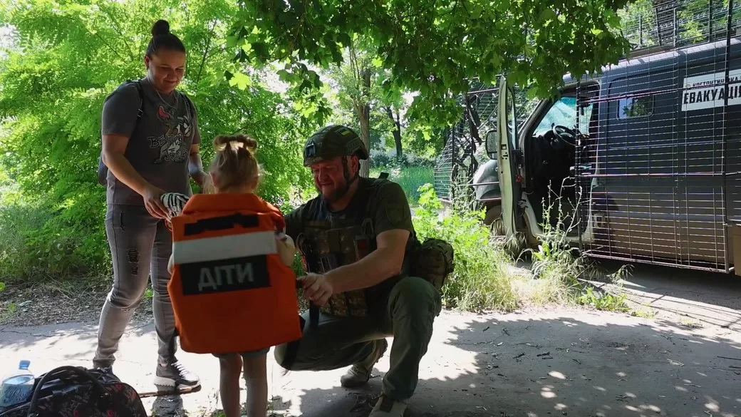 Евакуаційник та мама одягають бронежилет дівчинці з Костянтинівки Донецької області / Поліція Донеччини