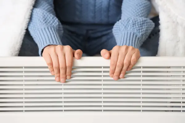 Жінка біля обігрівача / Фото: depositphotos