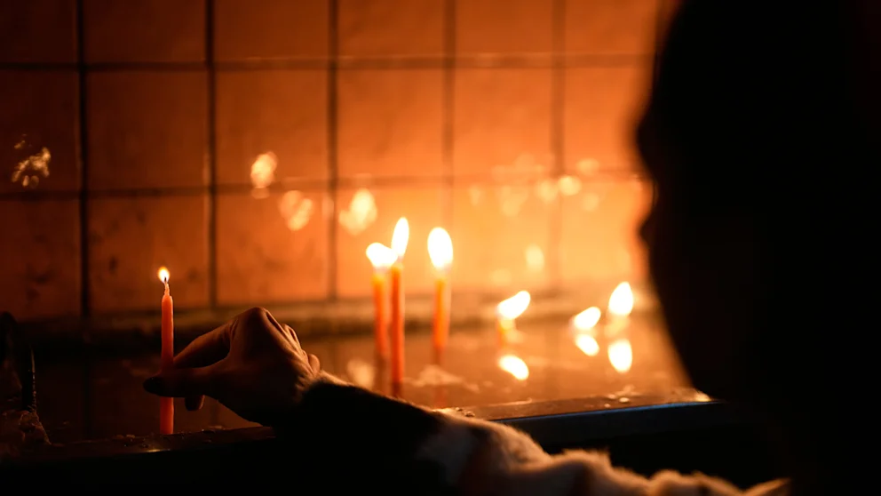 Жінка запалює свічку в базиліці Святого Антонія в Стамбулі у Святвечір / Фото: AP