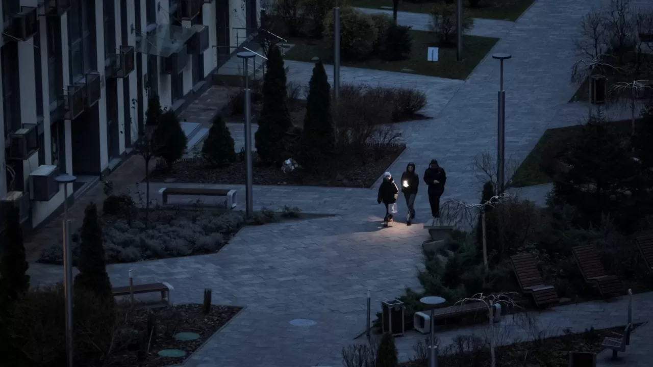 Люди використовують ліхтарики, коли йдуть пішки під час відключення електроенергії після того, як критична цивільна інфраструктура була пошкоджена внаслідок російських атак / Фото: Reuters