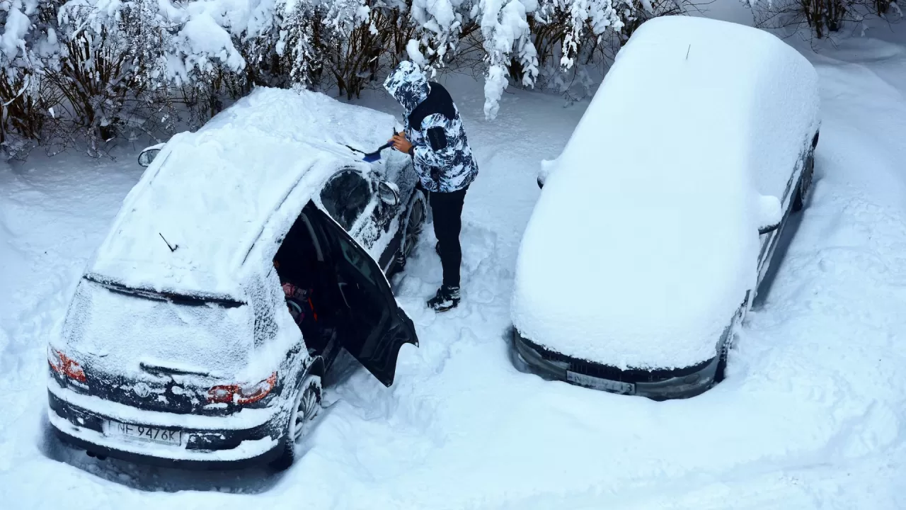 Чоловік прибирає сніг зі свого автомобіля після сильного снігопаду в Ольштині, Польща, 31 грудня 2025 року / Фото Reuters