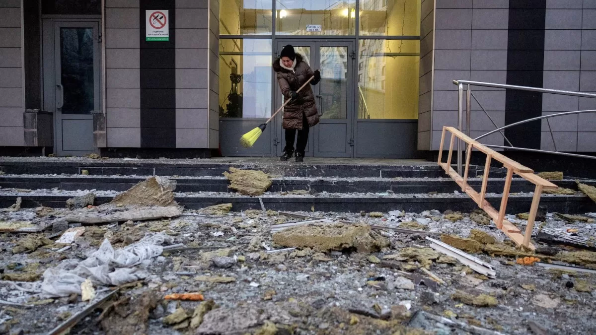 Женщина убирает обломки возле жилого дома, который был поврежден дроном во время российских ракетных и дроновых атак в Киеве, 3 февраля 2026 года / Фото Reuters
