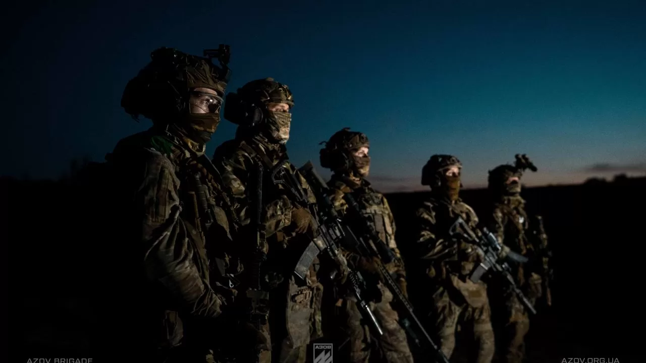 Пʼятеро екіпірованих бійців вдивляються у горизонт на фоні світанку