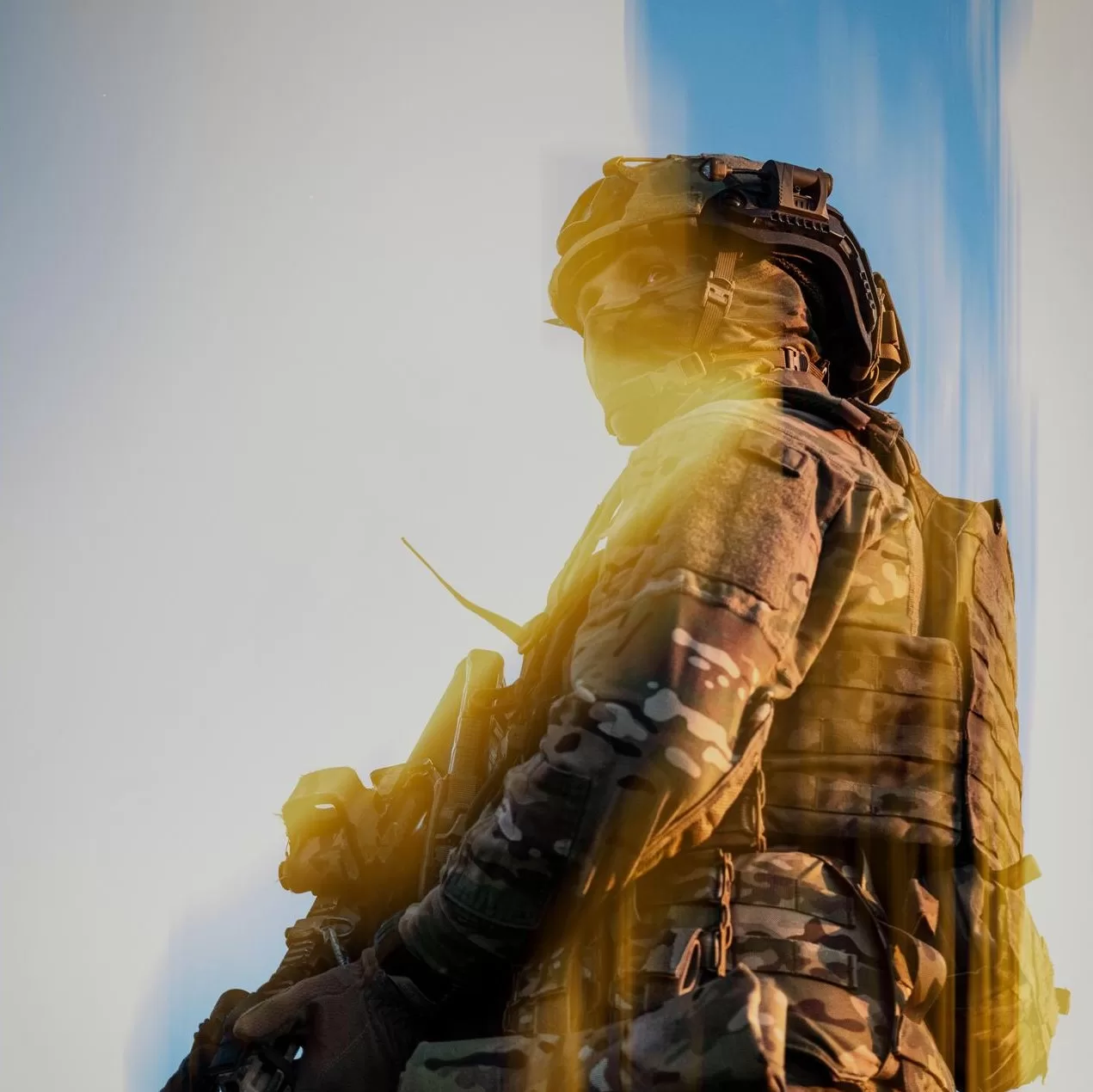 Споряджений боєць дивиться ліворуч, освітлений кольорами українського прапора
