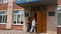 Співробітник СБУ стоїть біля входу до будівлі Чугуївської міськради / Фото: t.me/tipichnoe_xtz