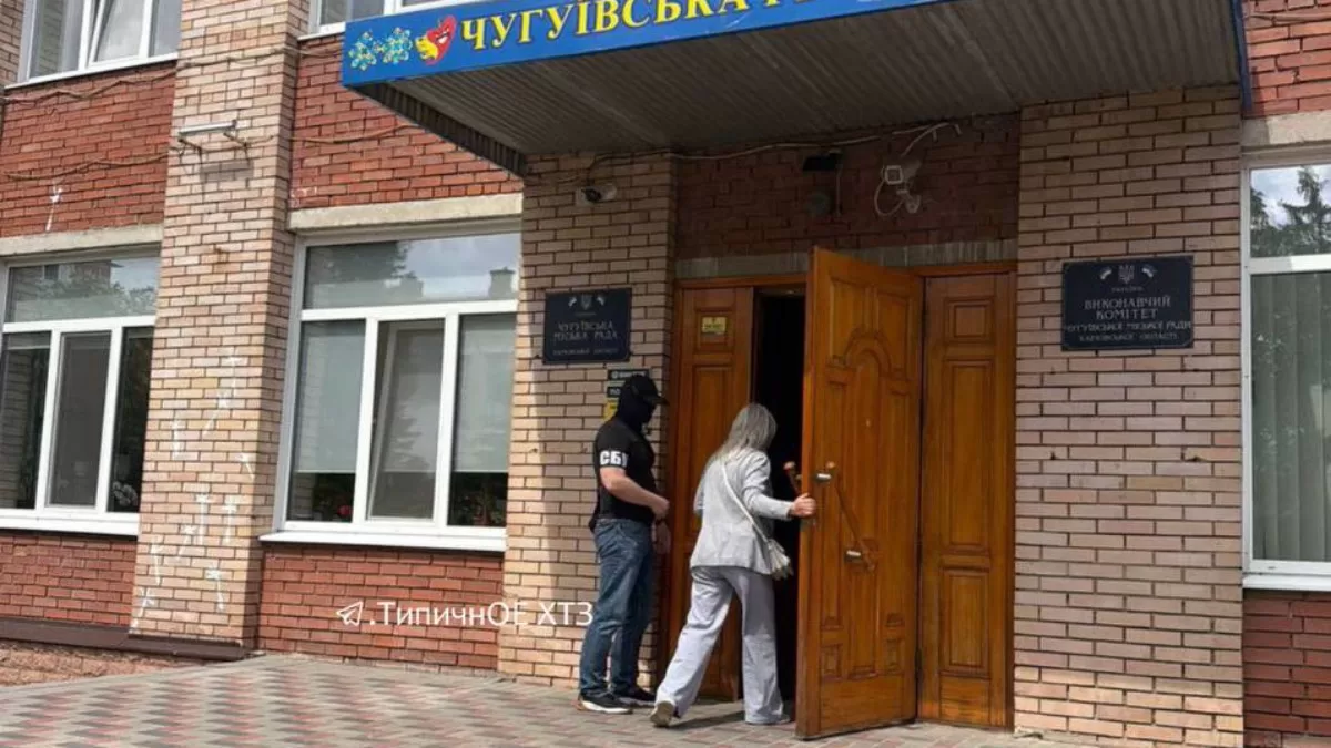 Співробітник СБУ стоїть біля входу до будівлі Чугуївської міськради / Фото: t.me/tipichnoe_xtz