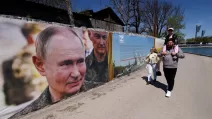 На виставці патріотичних фотографій у Сімферополі люди проходять повз банер із зображенням президента Росії Володимира Путіна та міністра оборони Андрія Белоусова / Фото: Reuters