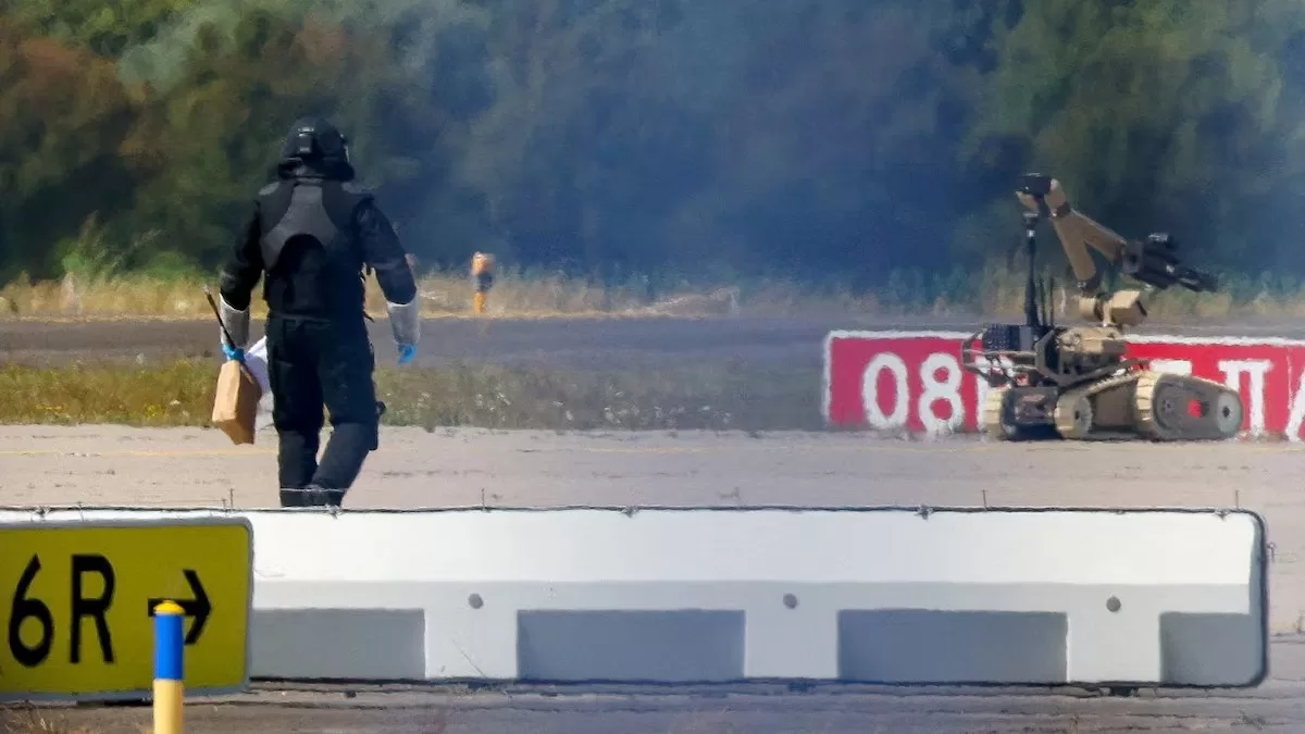 Поліцейський у захисному спорядженні йде поруч із роботом для знешкодження вибухівки (EOD) в аеропорту Лейпциг/Галле у Шкойдіці, Німеччина, 5 серпня 2026 року / Фото: Reuters