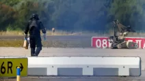 5 августа 2026 года в аэропорту Лейпциг/Галле в Шкеудице (Германия) полицейский в защитном снаряжении идет рядом с роботом для обезвреживания взрывных устройств (EOD) / Фото: REUTERS/Axel Schmidt