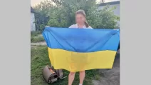 Одна з українок, яка повернулася з тимчасово окупованої території, з державним прапором України / Фото: Офіс Омбудсмана України