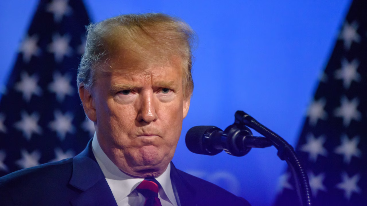 Дональд Трамп виступає перед мікрофонами на тлі прапорів США / Ілюстративне фото: Depositphotos